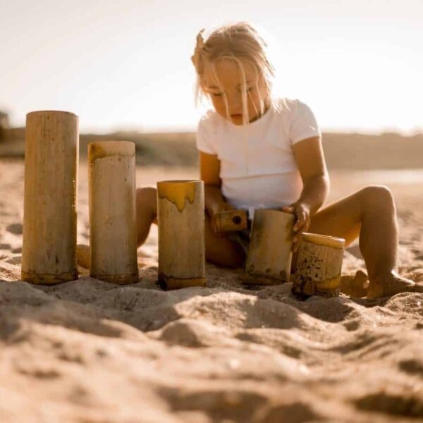 kid playing with bamboo in sand