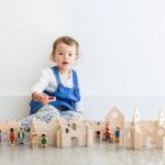 child playing with wooden village set