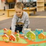 baby boy playing with wooden village set